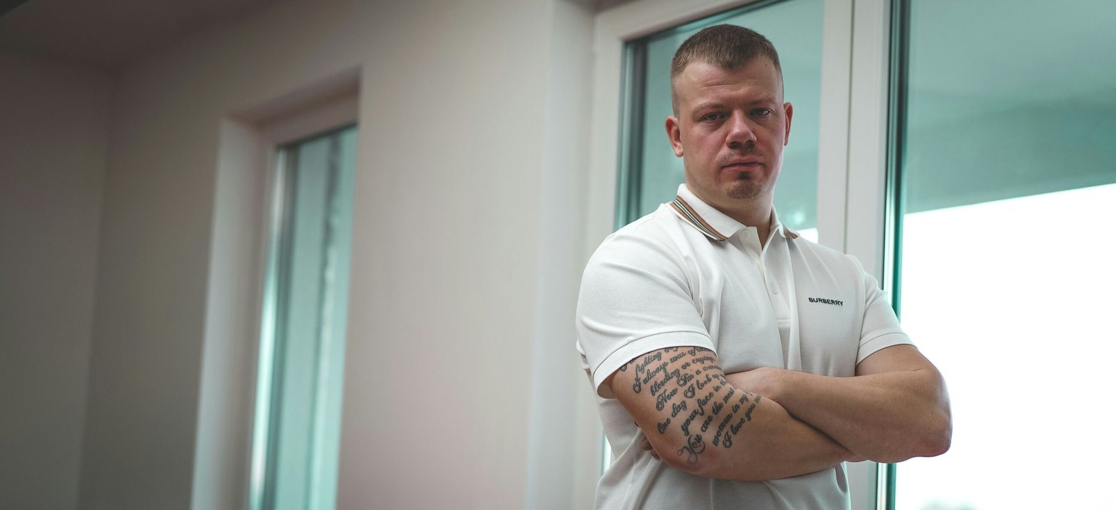 man in white polo shirt standing near white wall